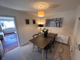 A dining room with a table and six chairs a lamp and wall art at Bayview Cottage in Southbourne