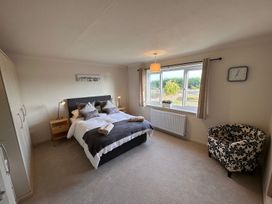 A bedroom with a bed pillows lamps a wardrobe a window and a patterned armchair at Bayview Cottage in Southbourne