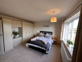 A bedroom with a bed pillows towels bedside tables lamps a large window wardrobe and plants at Bayview Cottage in Southbourne