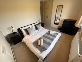 A bedroom with a double bed and bedside tables with lamps and a dresser and a full length mirror at Bayview Cottage in Southbourne
