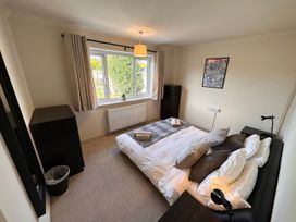 A bedroom with a bed pillows two black dressers a window with curtains and a framed picture on the wall at Bayview Cottage in Southbourne