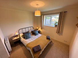 A bedroom with a double bed pillows bedside tables lamps a window and beige carpet at Bayview Cottage in Southbourne