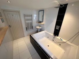A bathroom with a bathtub shower sink towel rack and mirror at Bayview Cottage in Southbourne