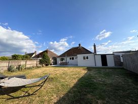 A backyard with a lawn hammock a patio table and chairs fenced garden at Bayview Cottage in Southbourne