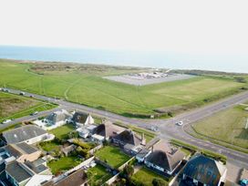 Aerial view of houses with gardens near a road and green fields by the sea at Bayview Cottage in Southbourne