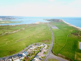 Aerial view of a coastal area with houses roads green fields a golf course and a beach at Bayview Cottage in Southbourne