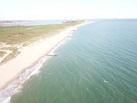 A sandy beach with green grassy area beside it and calm sea stretching to the horizon at Bayview Cottage in Southbourne