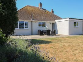 A house with a patio and chairs at Bayview Cottage in Southbourne