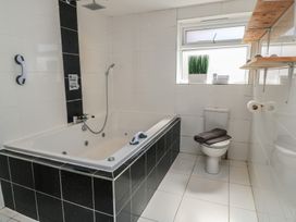 A bathroom featuring a bathtub, toilet, and shelves at Bayview Cottage Southbourne