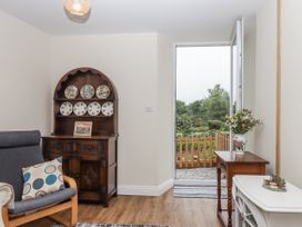 A living room with a sofa and a display cabinet at Aunty Junes Cottage Okehampton