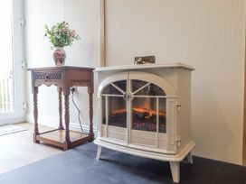 A living room with an electric fireplace and side table at Aunty Junes Cottage Okehampton