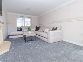 A living room with a beige sectional sofa a round wooden coffee table with a plant on it and a beige fireplace at 9 Beckett Close in Colwyn Bay