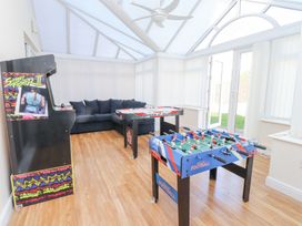 A game room with a street fighter II arcade machine a foosball table an air hockey table and a black sofa at 9 Beckett Close Colwyn Bay