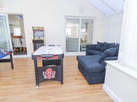 A games room with an air hockey table foosball table arcade machine and a sofa at 9 Beckett Close in Colwyn Bay