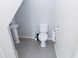 A small bathroom with a toilet a sink a toilet brush a trash bin a radiator and a toilet paper holder at 9 Beckett Close in Colwyn Bay