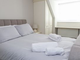 A bedroom with a bed with gray sheets pillows and rolled white towels near a window with blinds and a white wardrobe at 9 Beckett Close in Colwyn Bay