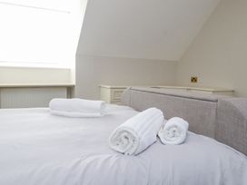 A bedroom with a bed with rolled white towels on it and a window in the background at 9 Beckett Close in Colwyn Bay