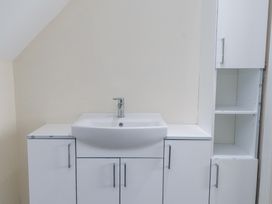 A white sink with faucet mounted on a white cabinet with storage shelves at 9 Beckett Close in Colwyn Bay