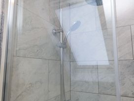 A shower area with a handheld shower head and tiled walls at 9 Beckett Close in Colwyn Bay