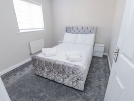 A bedroom with a bed with white bedding and rolled towels on top with bedside tables on each side at 9 Beckett Close in Colwyn Bay