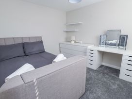 A bedroom with a grey bed a white dresser a white desk with mirrors and a lamp at 9 Beckett Close Colwyn Bay