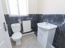 A bathroom with a white toilet and a white sink cabinet next to a window at 9 Beckett Close in Colwyn Bay