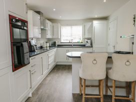 A kitchen with appliances and bar stools at 9 Beckett Close in Colwyn Bay