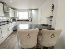 A kitchen with bar stools and a window at 9 Beckett Close in Colwyn Bay