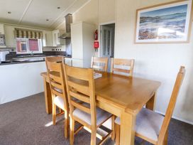 A kitchen and dining area with a wooden dining table and six chairs at Crathie Lodge in Banavie near Caol