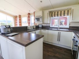A kitchen with white cabinets dark countertops microwave toaster kettle and coffee machine at Crathie Lodge Banavie near Caol