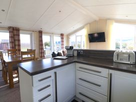 A kitchen with white cabinets wooden countertop and toaster next to a dining table with wooden chairs at Crathie Lodge Banavie near Caol