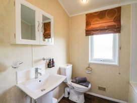 A bathroom with a sink toilet mirror cabinet and window with brown blind at Crathie Lodge in Banavie near Caol