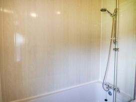 A bathroom with a bathtub and a shower head attached to the wall at Crathie Lodge Banavie near Caol