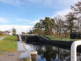 A canal lock with water and grassy banks with trees and houses nearby at Crathie Lodge in Banavie near Caol