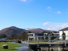 A canal lock with railings near residential buildings and hills in the background at Crathie Lodge in Banavie near Caol