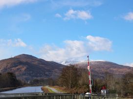 A canal with a barrier gate and walkway with hills and snow in the background at Crathie Lodge in Banavie near Caol