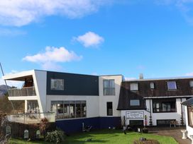 A hotel and restaurant building with a garden area and a clear blue sky at The Moorings Hotel in Banavie near Caol