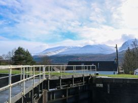 A canal lock with metal railings and a house in front of snow-covered mountains at Crathie Lodge in Banavie near Caol
