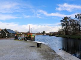 A canal with moored boats beside a gravel path and wooden buildings at Crathie Lodge in Banavie near Caol