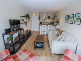 A living room with a television, sofa, and kitchenette at Oakley View Apartment in Porthmadog