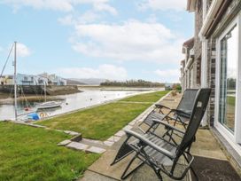 A patio area with chairs overlooking a waterway at Oakley View Apartment in Porthmadog