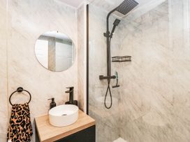 A bathroom with a shower, sink, and mirror at 2 Bakers Yard