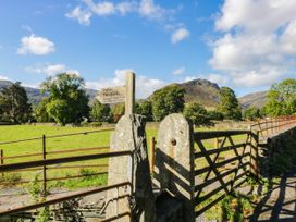 A gate with a sign in a field near trees and mountains at 2 Bakers Yard