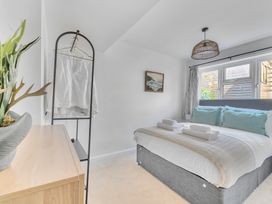 A bedroom with a bed and clothes rack at Palm House in Newquay