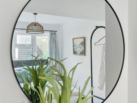 A bedroom with a mirror, plant, and hanging clothes at Palm House in Newquay