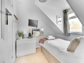 A bedroom with a single bed, television, and chest of drawers at Palm House in Newquay