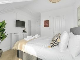 A bedroom with a bed, pillows, and a television at Palm House in Newquay