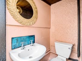 A bathroom with a sink, toilet, and mirror at Palm House in Newquay