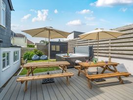 An outdoor space with tables, umbrellas, and a hot tub at Palm House in Newquay