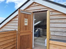 An open wooden door leading to a room with a blue couch and kitchen stools at The Halt in Maiden Newton